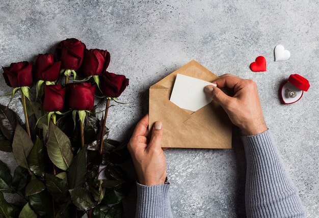 Mano de hombre de día de San Valentín con carta de amor envolvente con tarjeta de felicitación