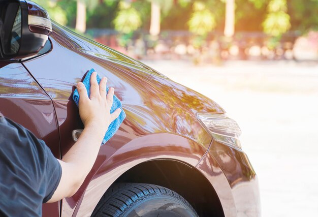 La mano del hombre es limpiar y encerar el coche.