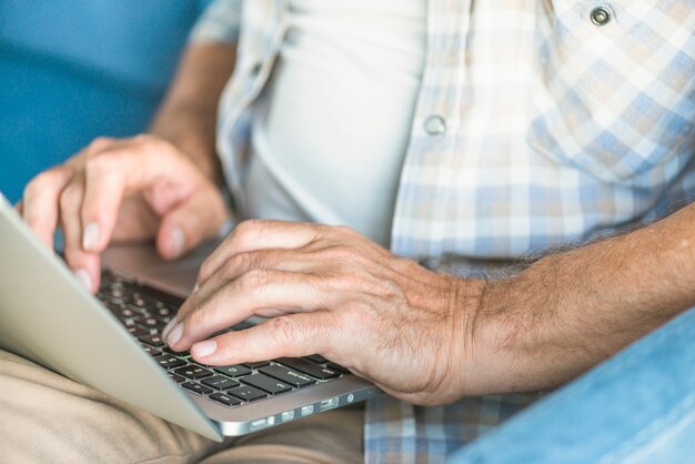 La mano de un hombre escribiendo en el teclado de la computadora portátil