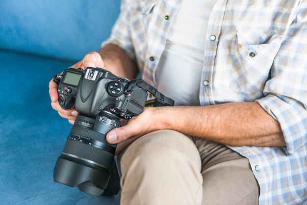 Foto gratuita la mano del hombre examinando la cámara dslr