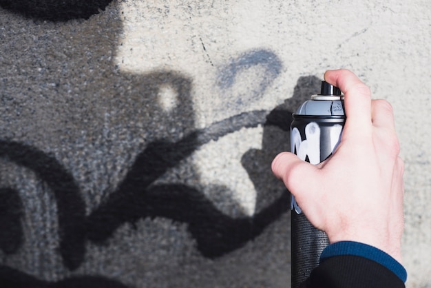 Mano del hombre haciendo graffiti con spray