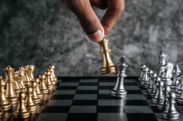 Mano del hombre jugando al ajedrez para la planificación empresarial y la comparación de la metáfora, enfoque selectivo