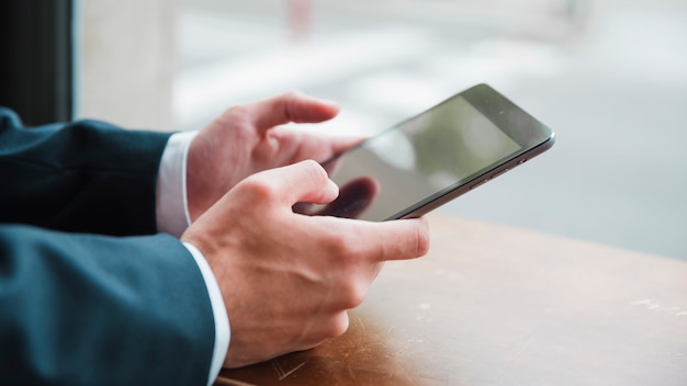 La mano del hombre de negocios usando teléfono inteligente en café