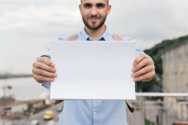 La mano del hombre con papel blanco en blanco