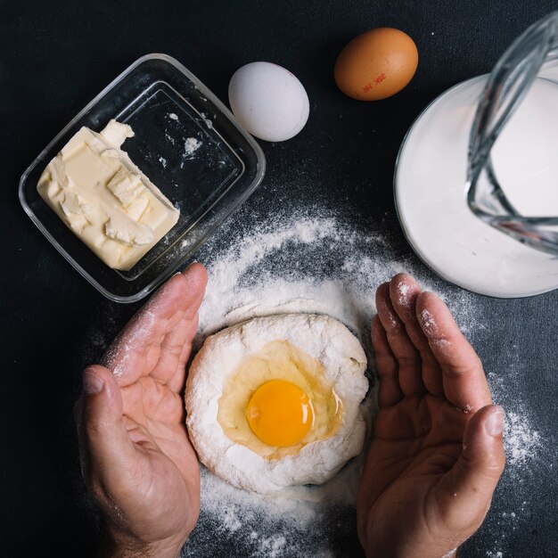 La mano del hombre que cubre el huevo york sobre la masa en el mostrador de la cocina
