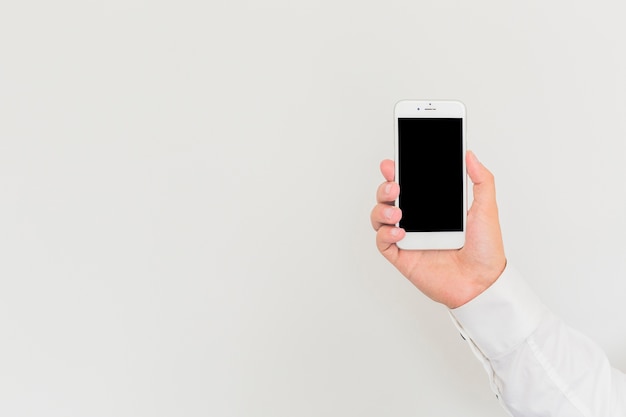 Mano del hombre que sostiene teléfono inteligente contra el fondo blanco