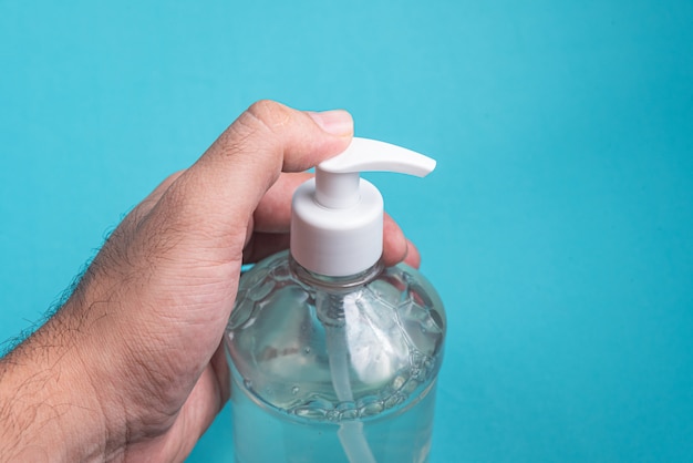 Foto gratuita mano del hombre en un recipiente con gel de alcohol en la luz azul