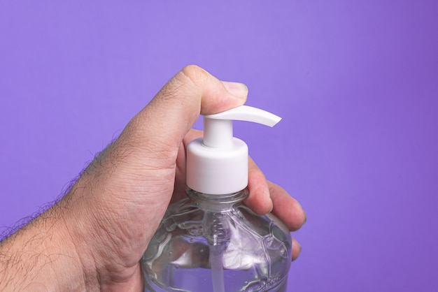 Foto gratuita mano del hombre en un recipiente con gel de alcohol en la luz azul