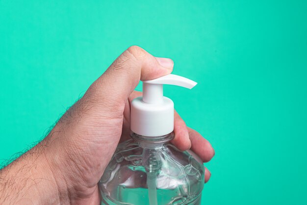 Mano del hombre en un recipiente con gel de alcohol en la luz azul