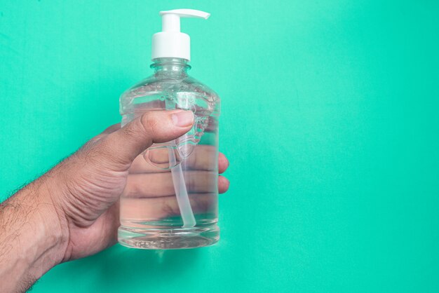 Mano del hombre en un recipiente con gel de alcohol en la luz azul