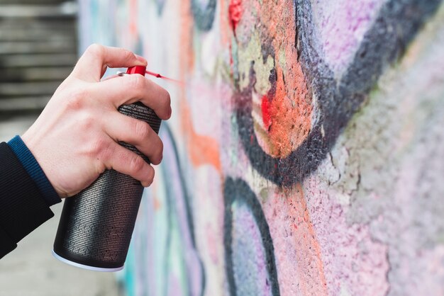 Mano del hombre rociando pintura roja con botella de spray