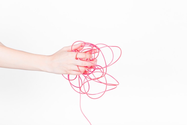 Foto gratuito mano humana con cable rojo enredado