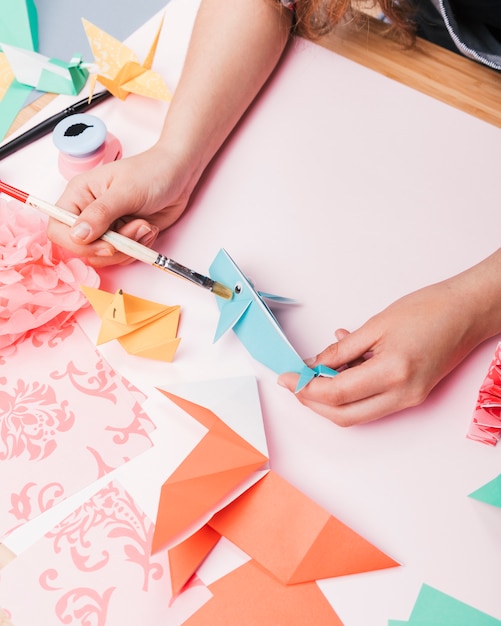 Mano humana pintando peces de origami con pincel