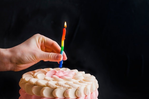 Mano humana poniendo velas en el pastel