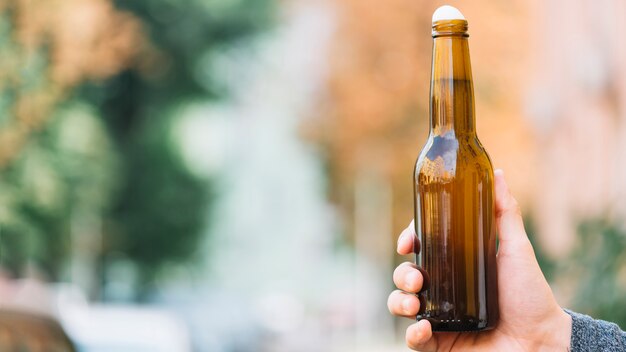 Mano humana sosteniendo la botella de cerveza