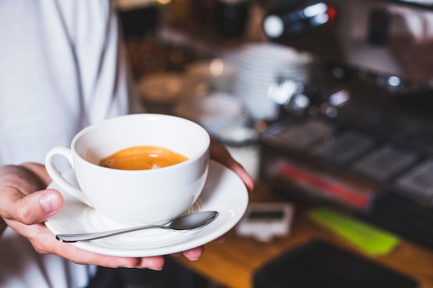 Mano humana sosteniendo una taza de café en la cafetería