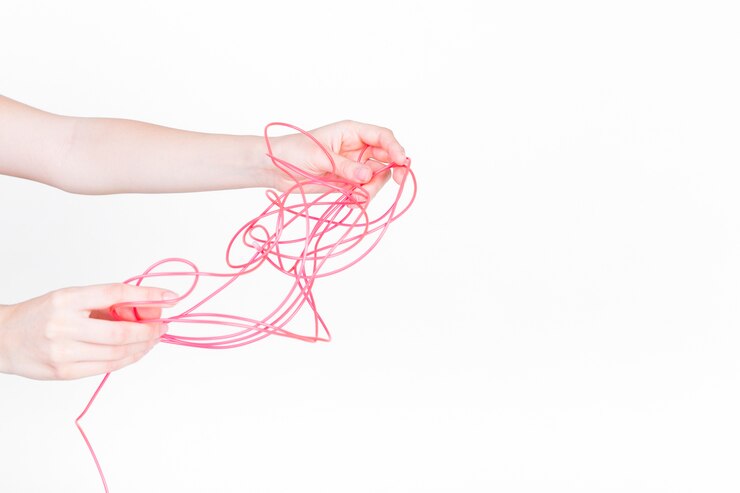 Foto gratuito mano humana tratando de desenredar el cable rojo sobre fondo blanco