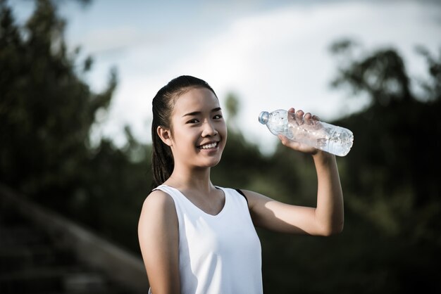 Mano joven de la aptitud de la mujer que sostiene la botella de agua después de correr el ejercicio