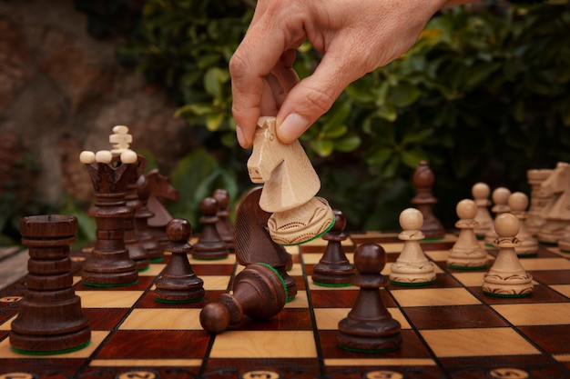 Mano jugando al ajedrez en el tablero clásico