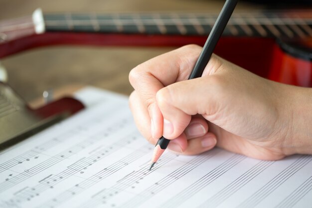 La mano con lápiz hoja y la música