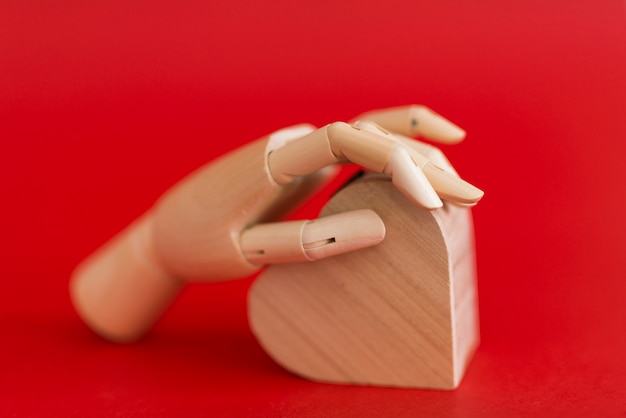 Mano de madera con corazón de madera en la mesa