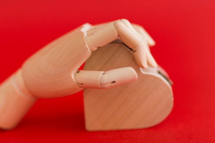 Foto gratuito mano de madera con corazón de madera