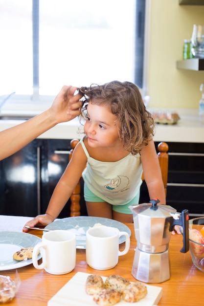 La mano de la madre tocando el cabello de la hija durante el desayuno