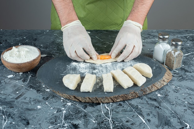 Mano masculina en guantes haciendo bolas de masa de camarones en la mesa de mármol.