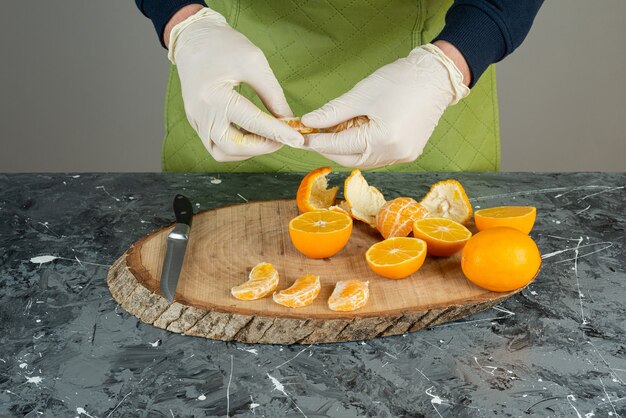 Foto gratuita mano masculina en guantes sosteniendo segmentos de mandarina en la mesa.