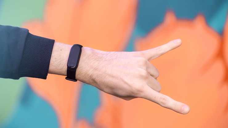 Foto gratuito una mano masculina mostrando signo de rock con pulsera de fitness, fondo multicolor