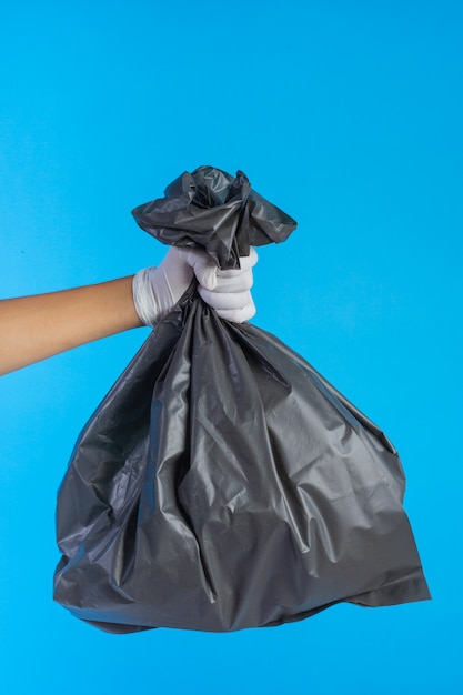 Foto gratuita la mano masculina que sostiene una bolsa de basura y un azul.