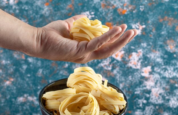 Mano masculina que sostiene el nido de tagliatelle.