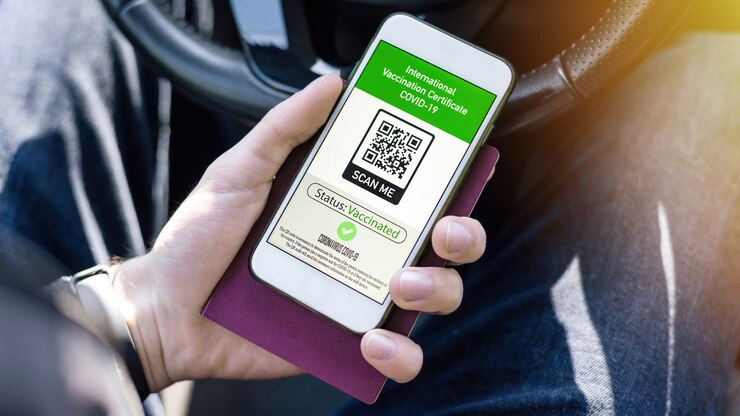 Foto gratuito mano masculina que sostiene el pasaporte y el teléfono inteligente con el código qr del certificado de vacunación internacional covid-19 en un automóvil