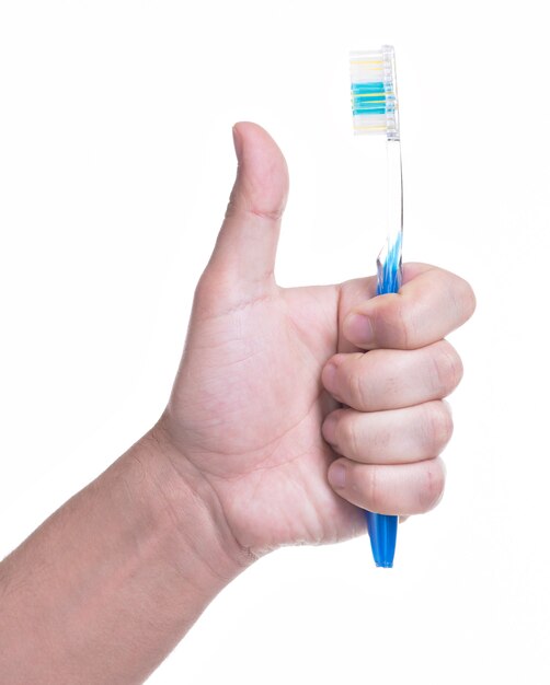 Mano masculina sostiene el cepillo de dientes con el pulgar hacia arriba signo - aislado en blanco.