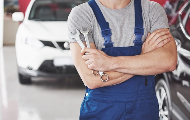 Mano de mecánico de automóviles con llave. Garaje de reparación de automóviles.