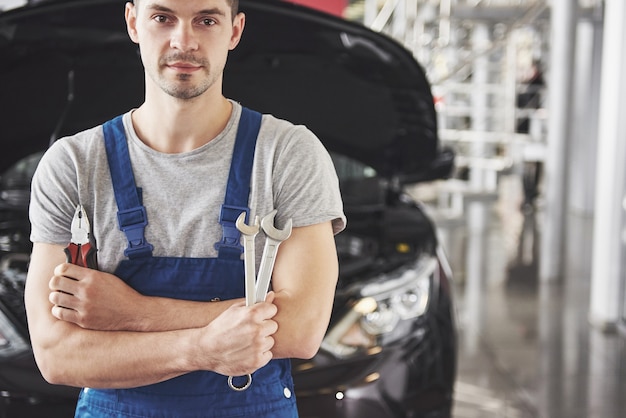 Mano de mecánico de automóviles con llave. Garaje de reparación de automóviles.