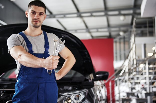 Mano de mecánico de automóviles con llave. Garaje de reparación de automóviles.