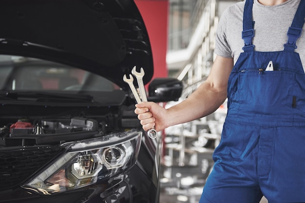 Mano de mecánico de automóviles con llave. Garaje de reparación de automóviles.