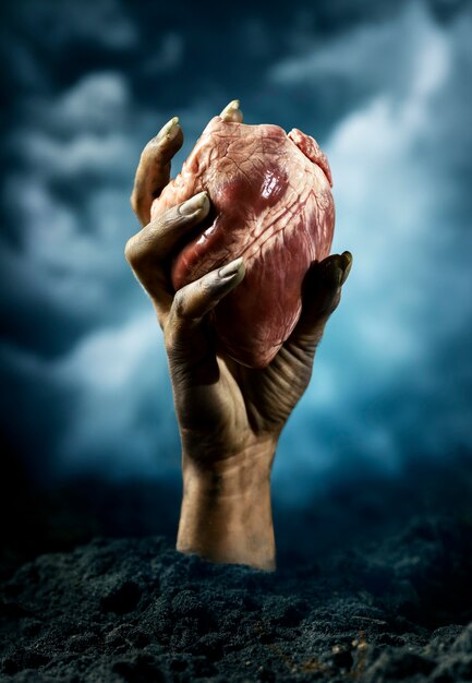 Mano de miedo mujer zombie sosteniendo un corazón