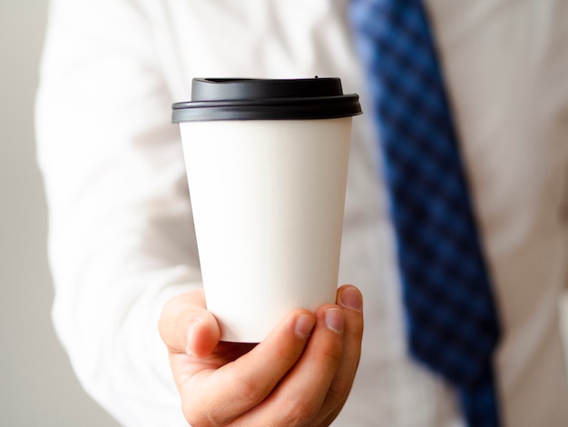 Mano mostrando maqueta de taza de café