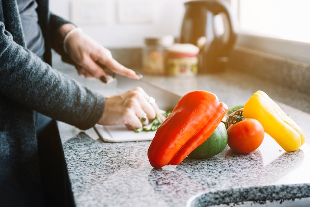 Mano de mujer cerca de verduras frescas en el mostrador de la cocina