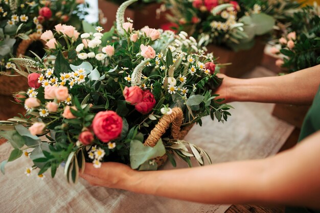 Mano de mujer con cesta de flores frescas