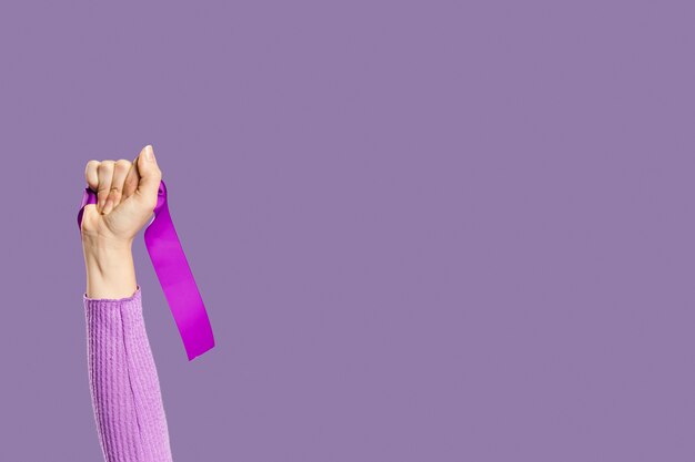 Mano de mujer con cinta violeta y copia espacio
