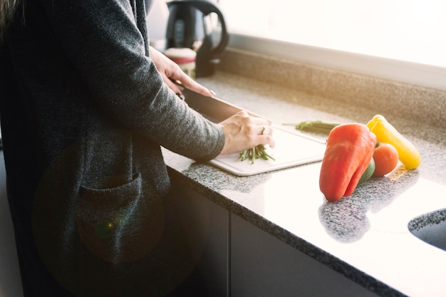 Mano de mujer cortar verduras en el mostrador de la cocina