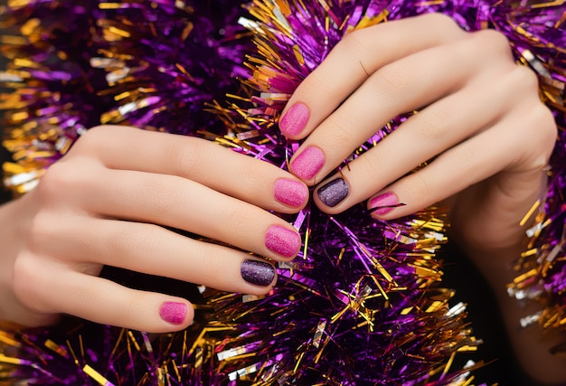 Mano de mujer con diseño de uñas de Navidad y Año Nuevo sostener esfera de juguete brillante