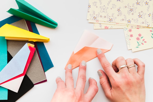 Mano de mujer haciendo avión de papel sobre fondo blanco