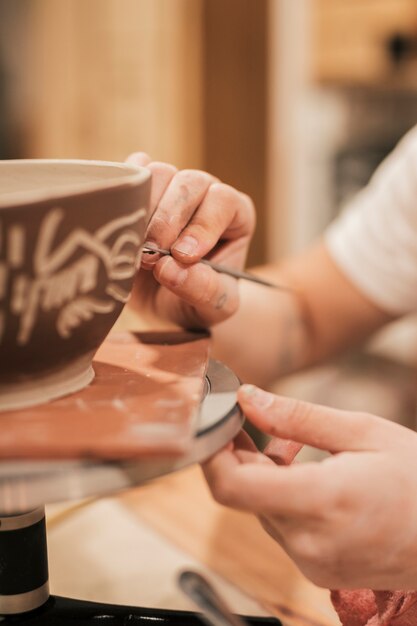 Mano de mujer haciendo diseño en tazón pintado.