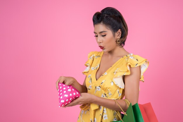 Mano de la mujer de la moda de los jóvenes que sostiene la cartera y los panieres