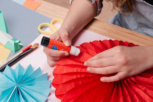 Mano de mujer pegando papel de origami mientras hace flor de origami