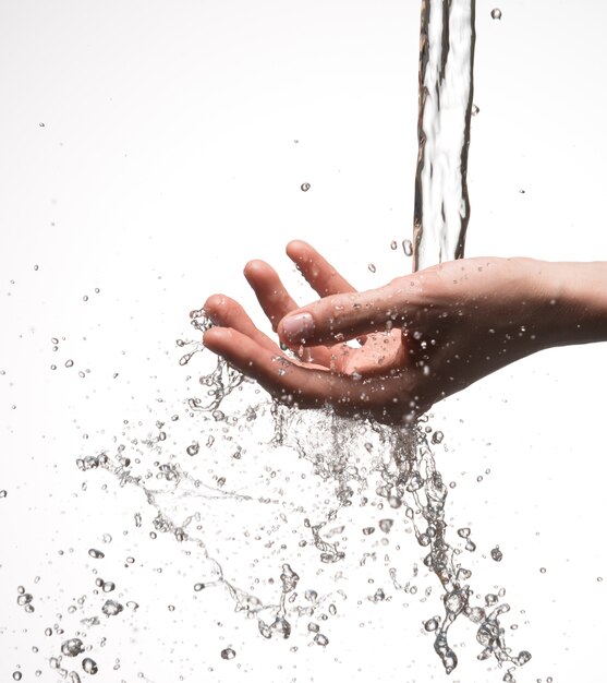 Mano de mujer de primer plano bajo la corriente de salpicaduras de agua